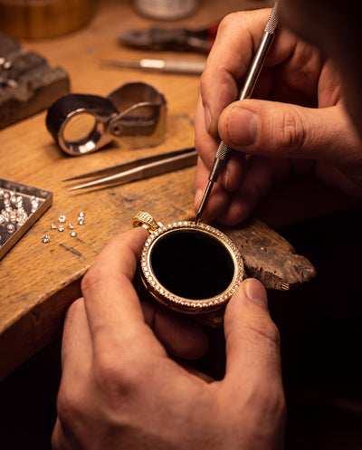 A jeweller setting a stone into the medallion at a workbench
